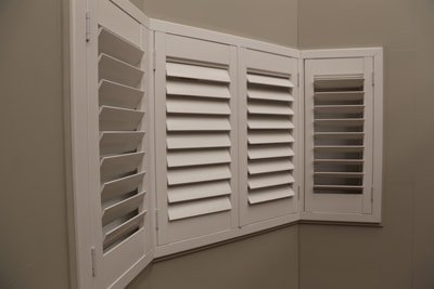 White plantation shutters wrapping around 3 walls