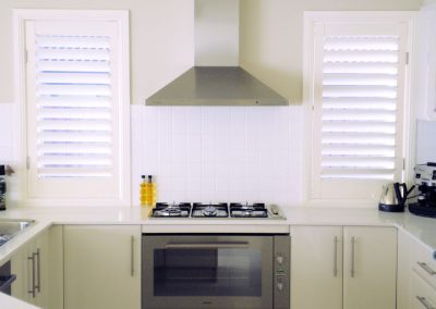 Symmetrical view of kitchen with plantation shutters on either side