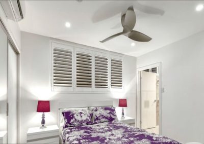 upscale hotel room with plantation shutters above bed
