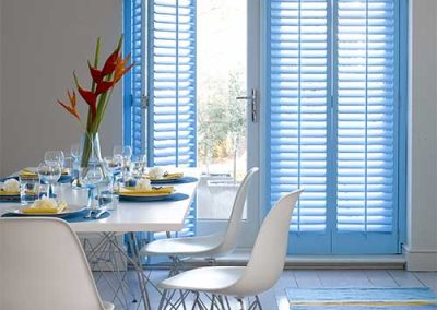 sky blue plantation shutters behind kitchen table