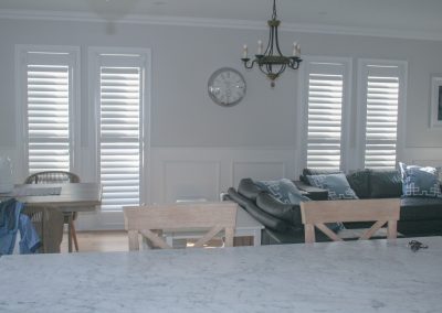 lounge room and kitchen view with plantation shutters
